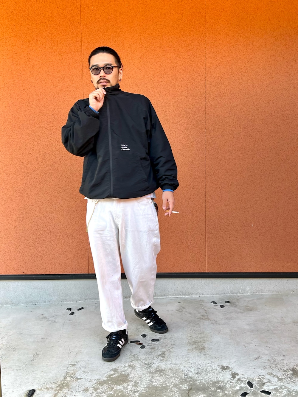 ブラック系のスニーカー、ホワイト系のデニムパンツ、ブラック系のナイロンジャケットを着用したメンズの冬コーディネートの2枚目の写真