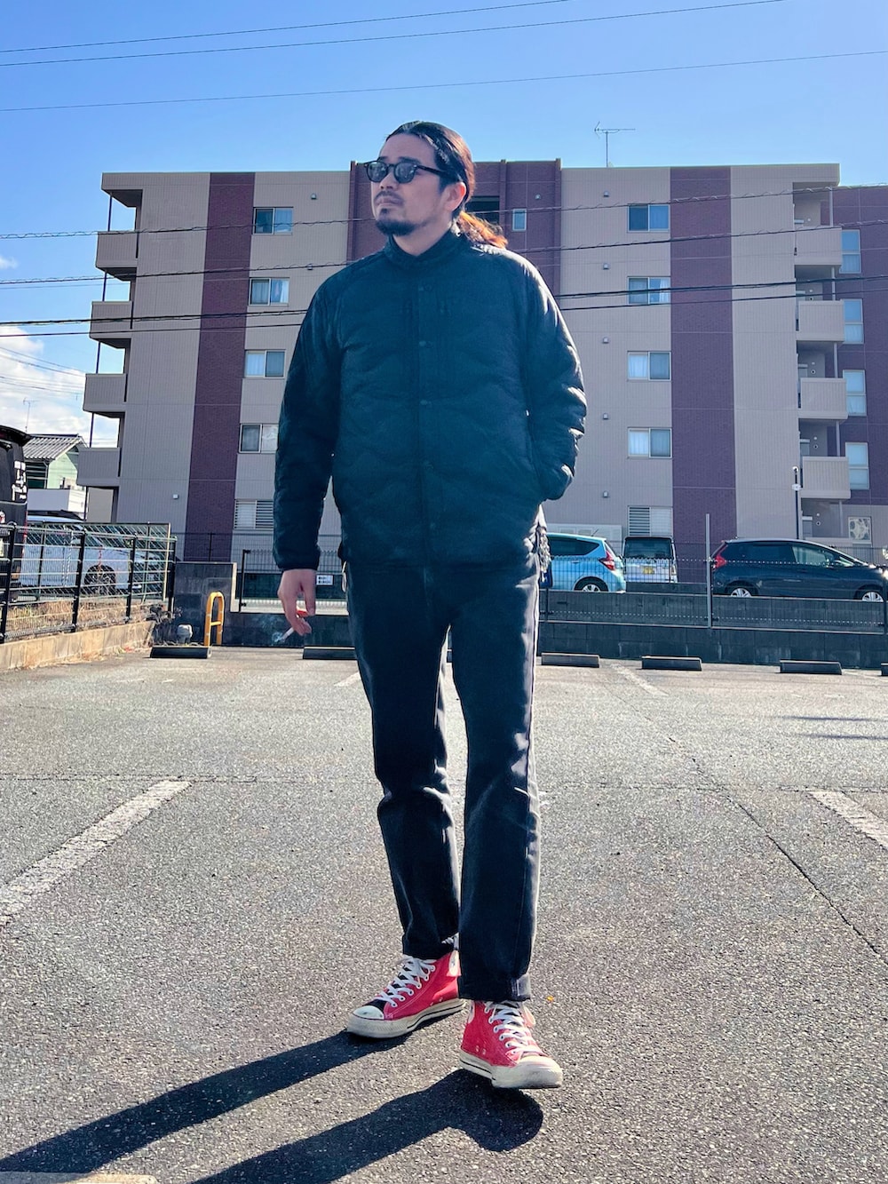 ブラック系のジャケット/アウター、ブラック系のデニムパンツ、レッド系のスニーカーを着用したメンズの冬コーディネートの3枚目の写真