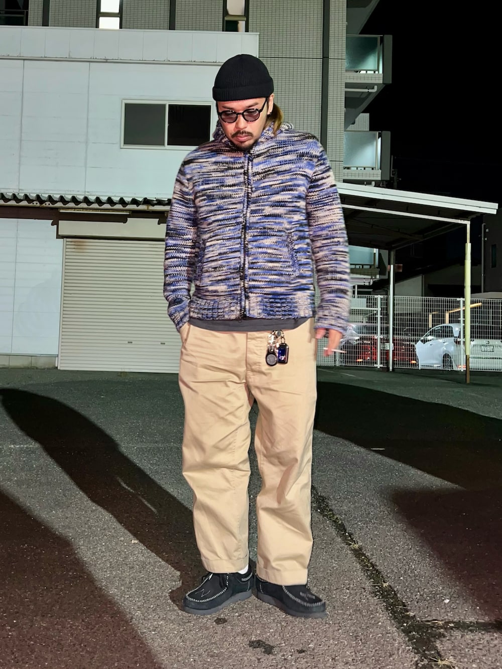 ブルー系のニット/セーター、ブラック系のTシャツ/カットソー、ベージュ系のチノパンツを着用したメンズの秋コーディネートの2枚目の写真