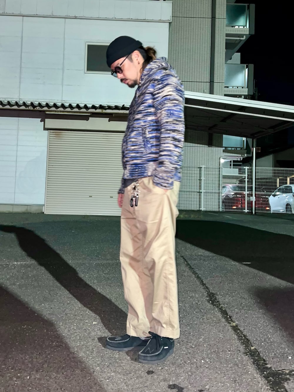 ブルー系のニット/セーター、ブラック系のTシャツ/カットソー、ベージュ系のチノパンツを着用したメンズの秋コーディネートの3枚目の写真