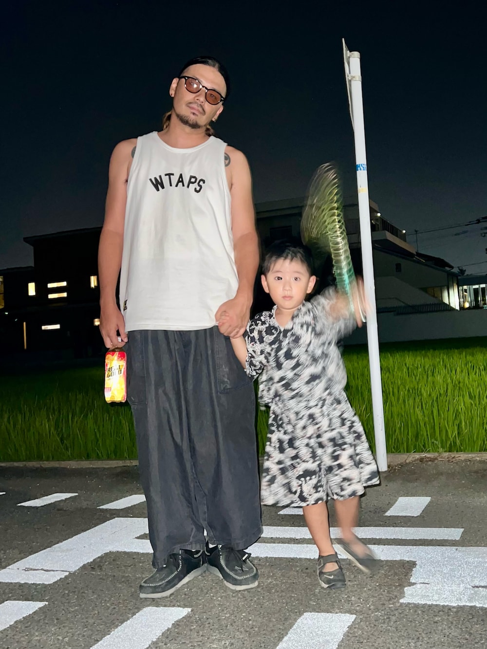 ブラック系のパンツ、ホワイト系のタンクトップ、ブラック系のスニーカーを着用したメンズの夏コーディネートの2枚目の写真