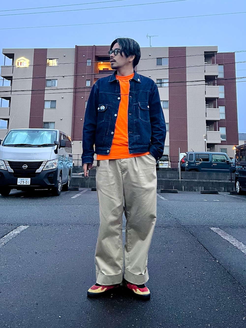 ベージュ系のチノパンツ、ブルー系のデニムジャケット、オレンジ系のTシャツ/カットソーを着用したメンズの春コーディネートの2枚目の写真
