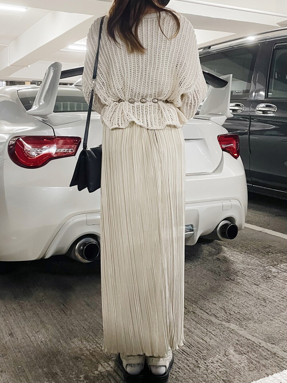 ホワイト系のサンダル、ホワイト系のスカート、ベージュ系のニット/セーターを着用したレディースの冬コーディネートの2枚目の写真