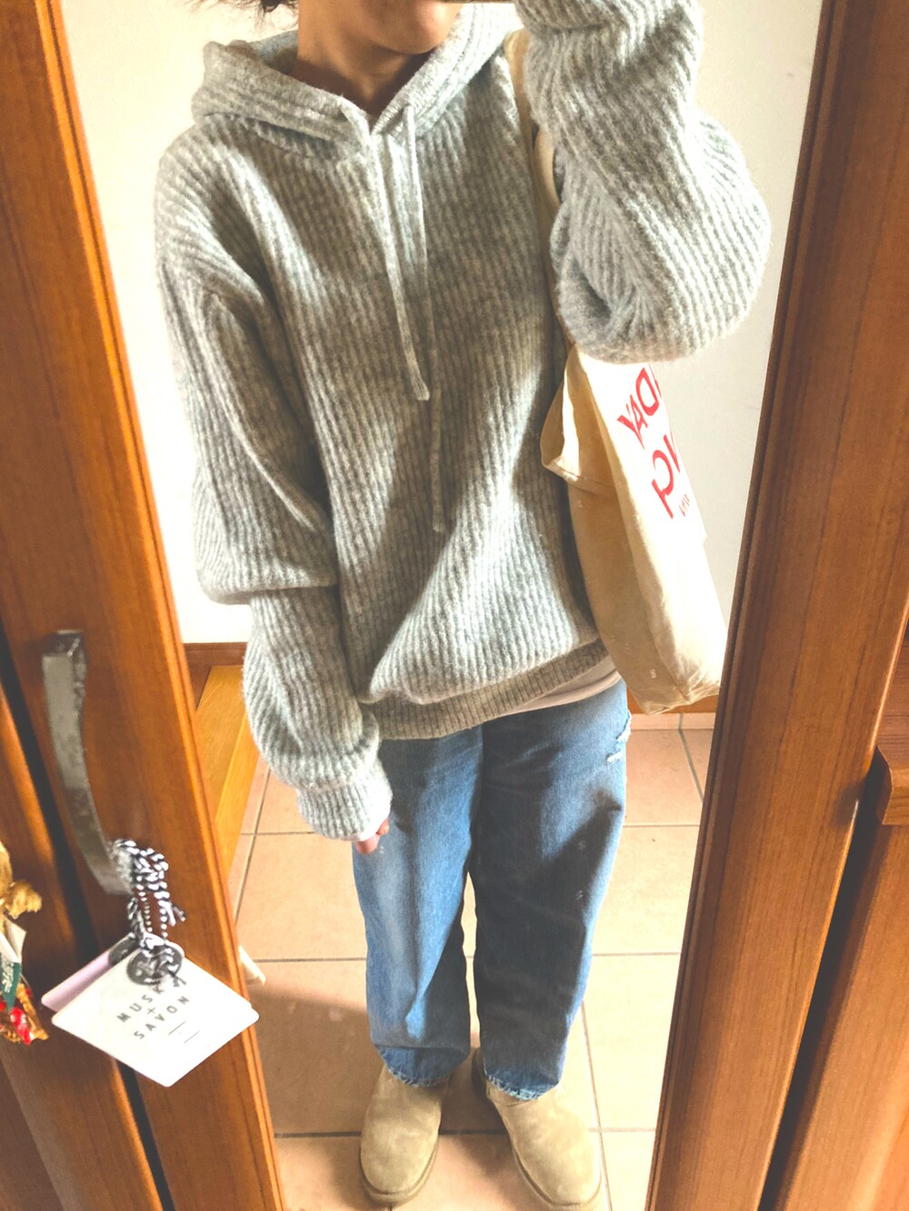 グレー系のニット/セーター、ブルー系のデニムパンツ、ベージュ系のブーツを着用したレディースの冬コーディネートの2枚目の写真