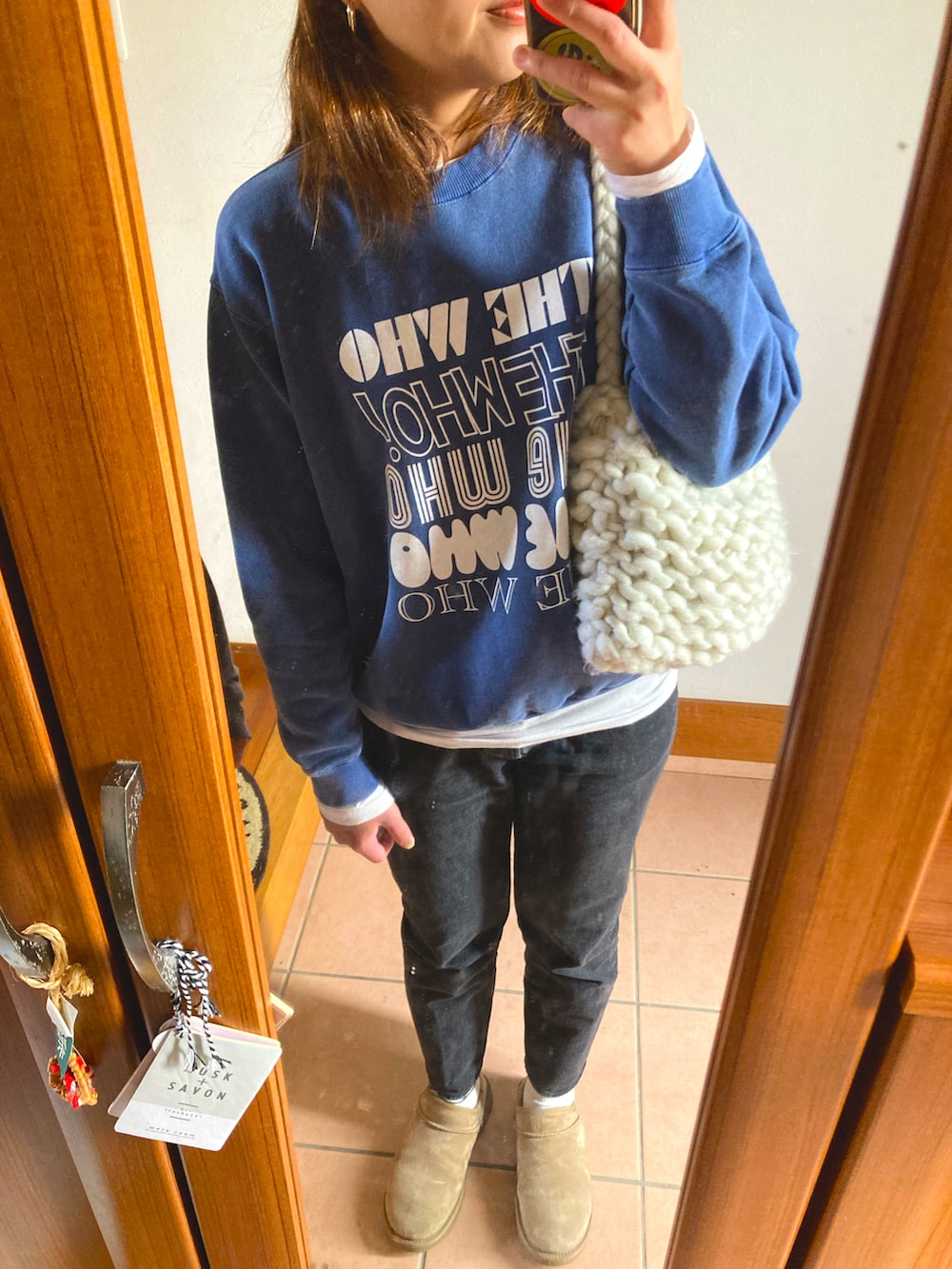 ブラック系のデニムパンツ、ブルー系のスウェット、ホワイト系のショルダーバッグを着用したレディースの冬コーディネートの3枚目の写真