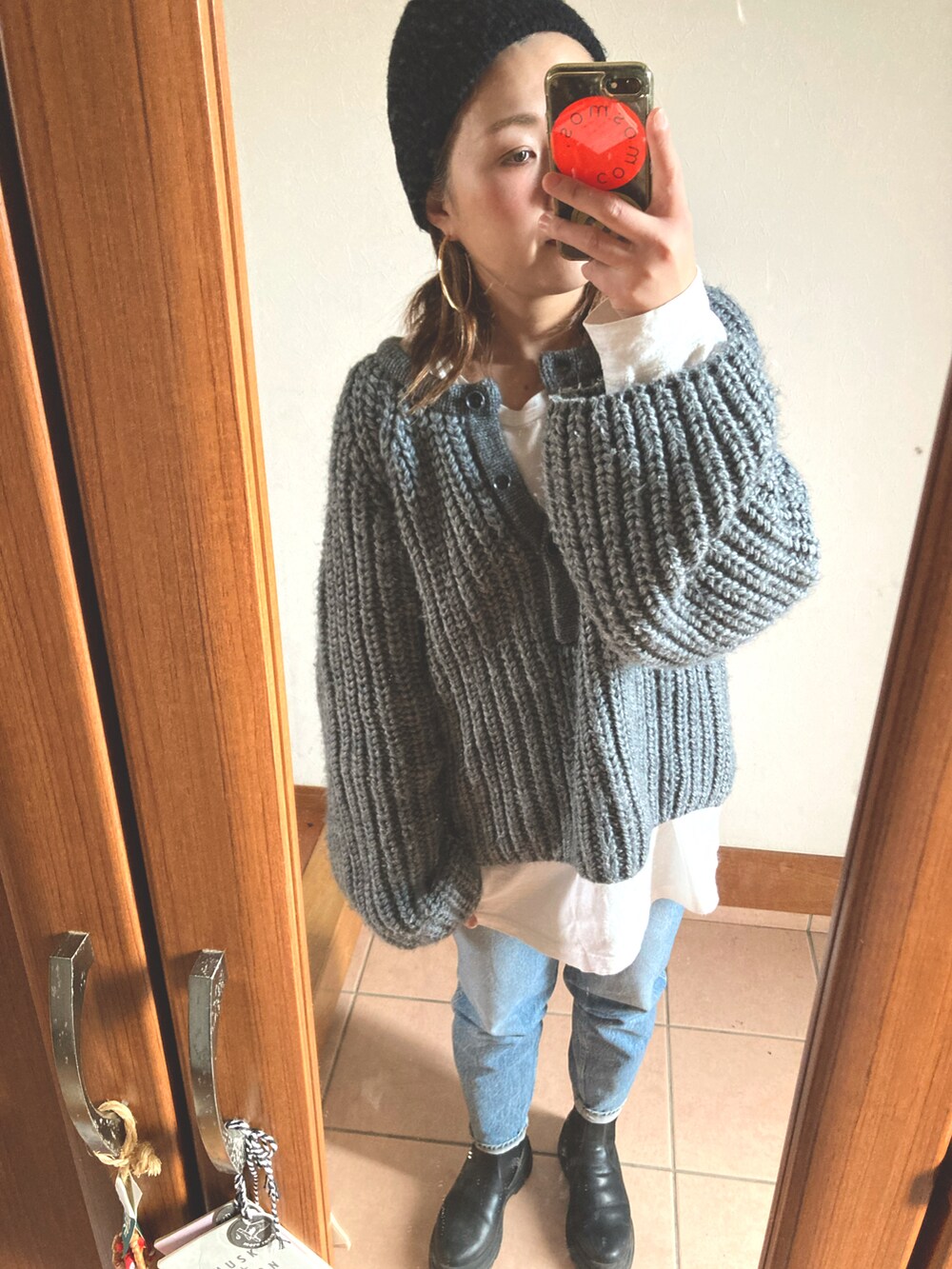 グレー系のニット/セーター、ホワイト系のTシャツ/カットソー、ブルー系のデニムパンツを着用したレディースの冬コーディネートの2枚目の写真