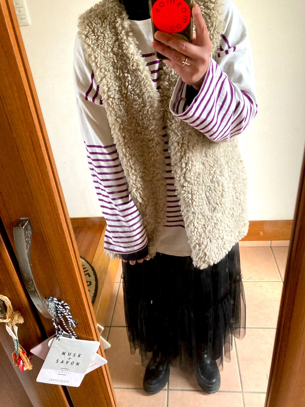 パープル系のTシャツ/カットソー、ブラック系のスカート、ブラック系のブーツを着用したレディースの冬コーディネートの4枚目の写真