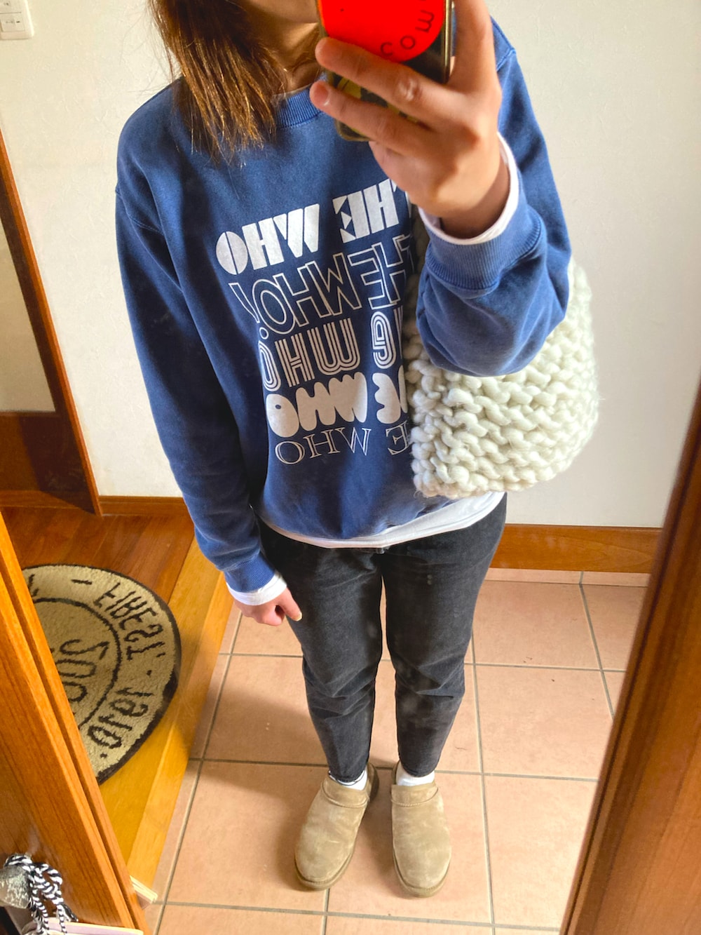 ブラック系のデニムパンツ、ブルー系のスウェット、ホワイト系のショルダーバッグを着用したレディースの冬コーディネートの2枚目の写真