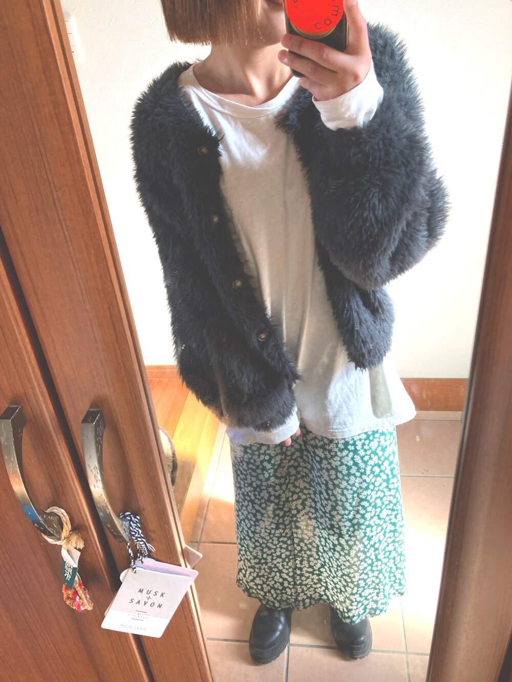 グリーン系のスカート、ホワイト系のTシャツ/カットソー、グレー系のカーディガン/ボレロを着用したレディースの冬コーディネートの2枚目の写真