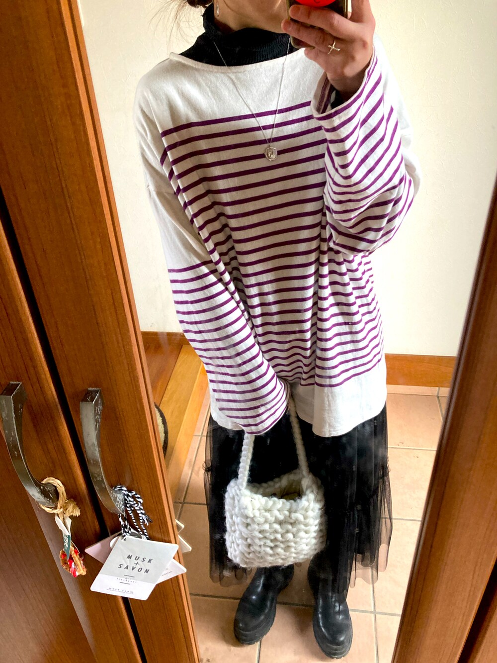 パープル系のTシャツ/カットソー、ブラック系のスカート、ブラック系のブーツを着用したレディースの冬コーディネートの2枚目の写真