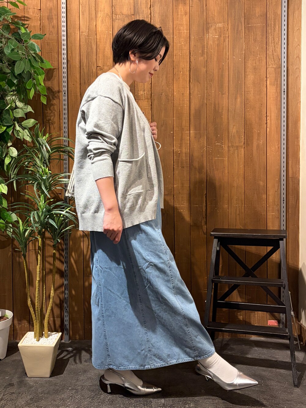 グレー系のニット/セーター、ブルー系のスカート、ホワイト系のTシャツ/カットソーを着用したレディースの秋コーディネートの4枚目の写真