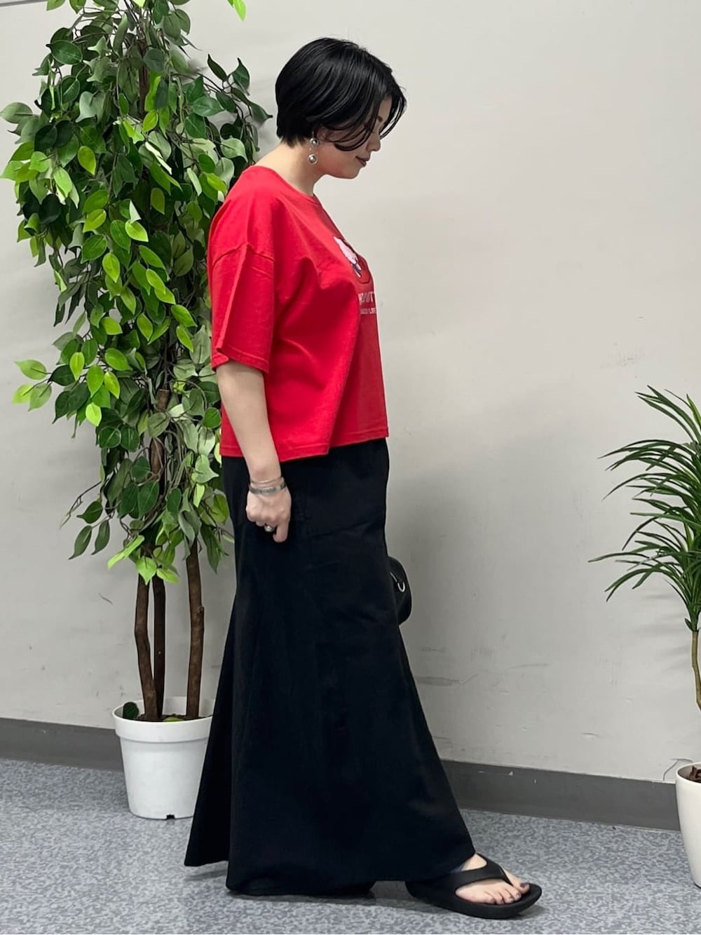 レッド系のTシャツ/カットソー、ブラック系のスカート、ブラック系のショルダーバッグを着用したレディースの春コーディネートの2枚目の写真