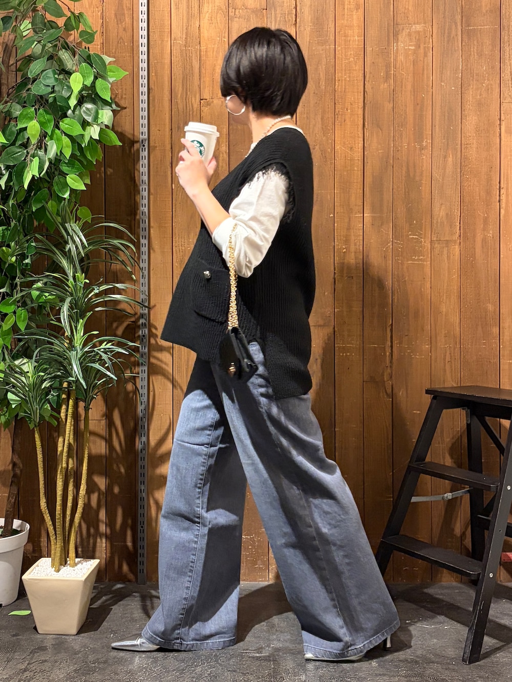 ブラック系のデニムパンツ、ホワイト系のTシャツ/カットソー、ブラック系のベストを着用したレディースの秋コーディネートの2枚目の写真