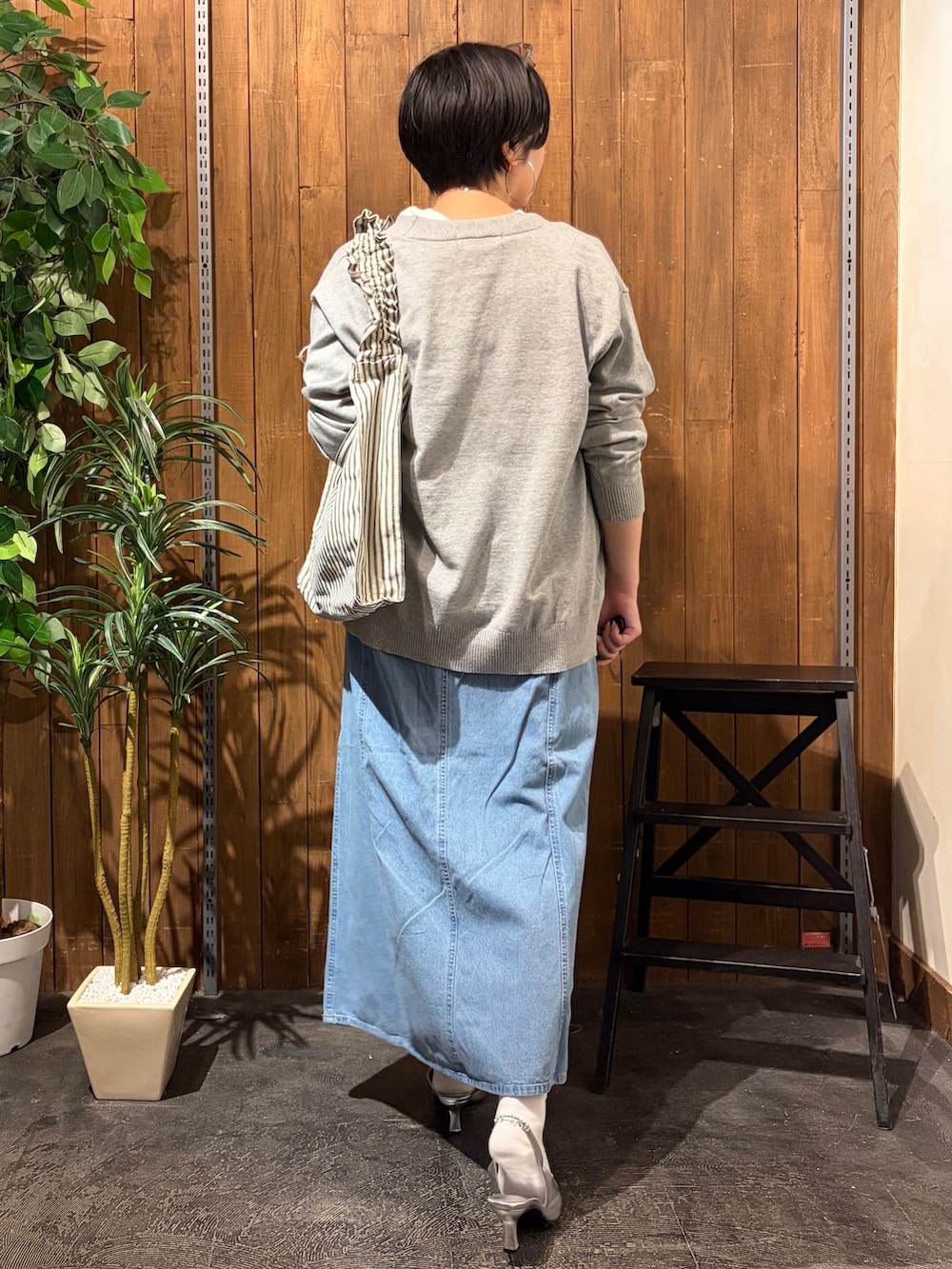 グレー系のニット/セーター、ブルー系のスカート、ホワイト系のTシャツ/カットソーを着用したレディースの秋コーディネートの3枚目の写真