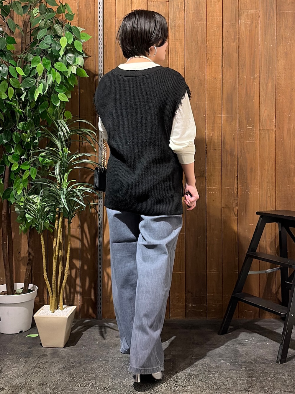 ブラック系のデニムパンツ、ホワイト系のTシャツ/カットソー、ブラック系のベストを着用したレディースの秋コーディネートの3枚目の写真
