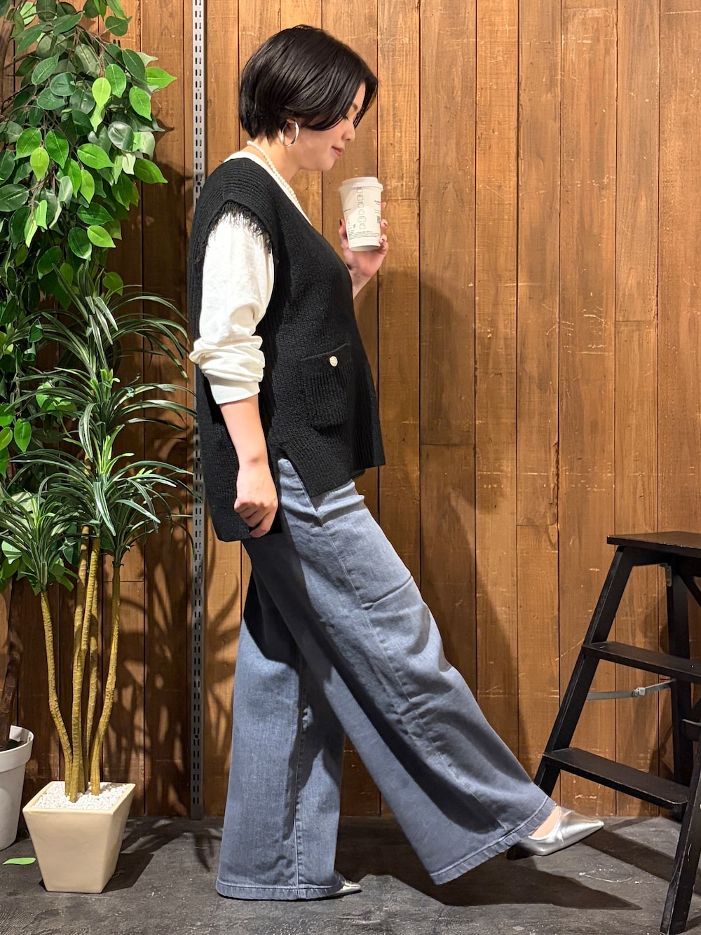 ブラック系のデニムパンツ、ホワイト系のTシャツ/カットソー、ブラック系のベストを着用したレディースの秋コーディネートの4枚目の写真