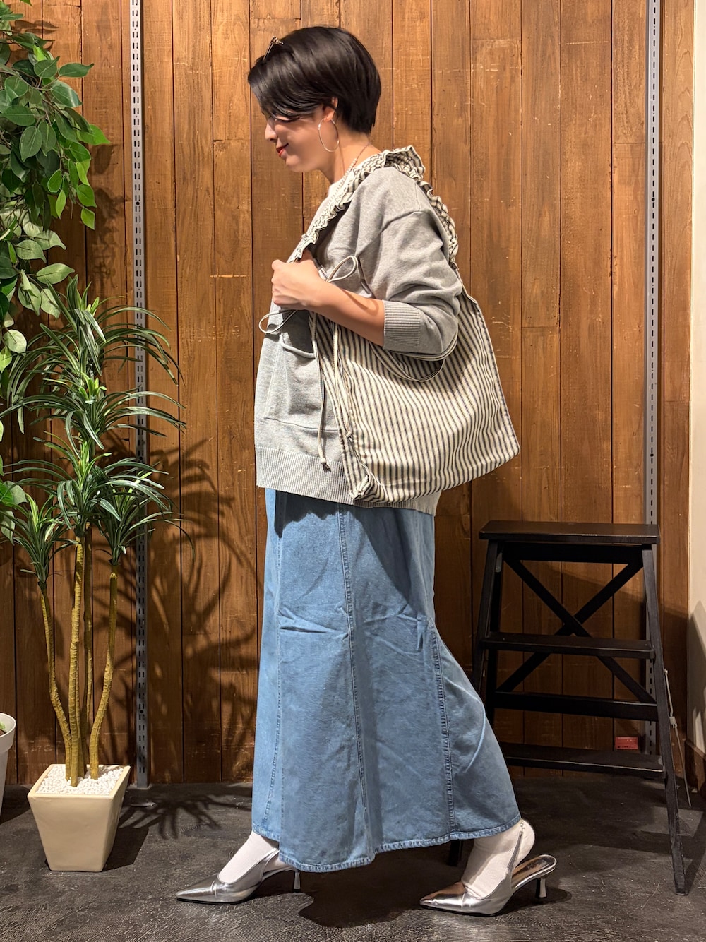 グレー系のニット/セーター、ブルー系のスカート、ホワイト系のTシャツ/カットソーを着用したレディースの秋コーディネートの2枚目の写真