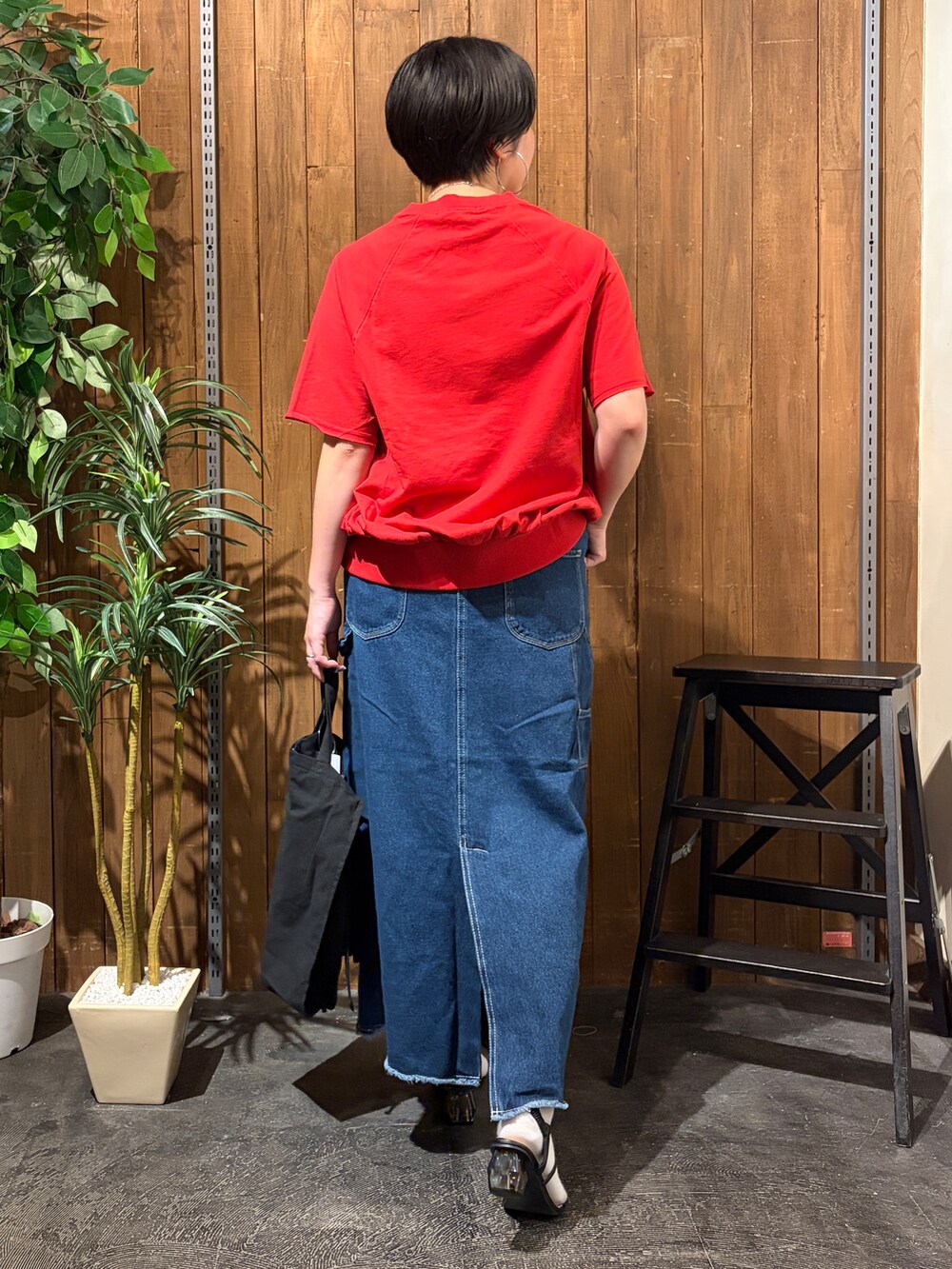 レッド系のTシャツ/カットソー、ブルー系のスカート、ブラック系のトートバッグを着用したレディースの夏コーディネートの2枚目の写真