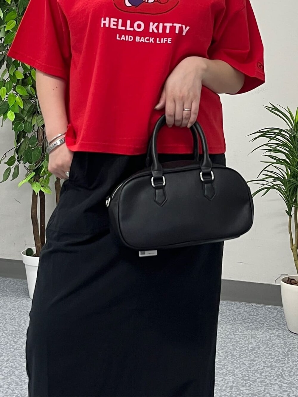 レッド系のTシャツ/カットソー、ブラック系のスカート、ブラック系のショルダーバッグを着用したレディースの春コーディネートの7枚目の写真