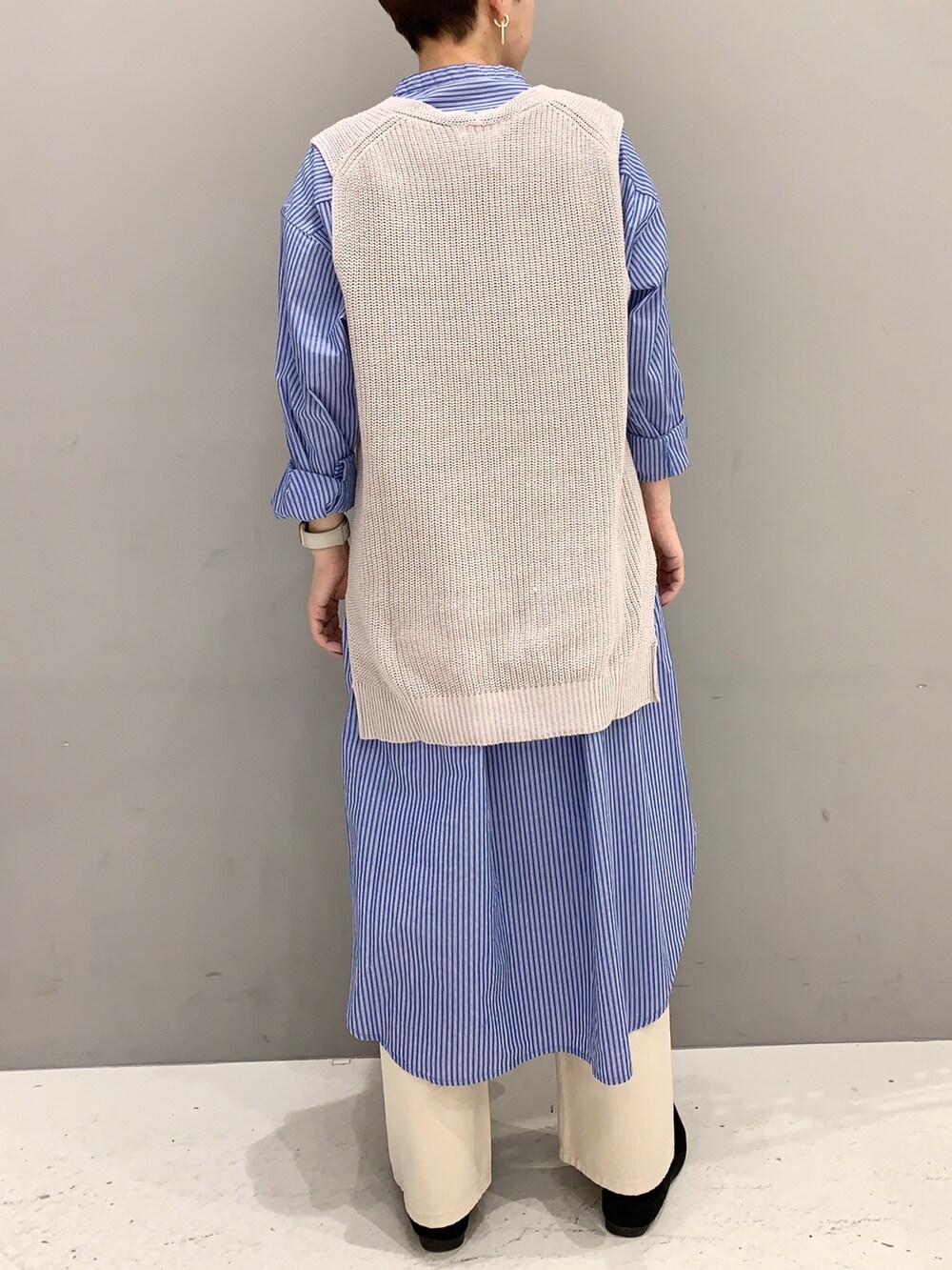 ブルー系のシャツワンピース、ベージュ系のベスト、ベージュ系のデニムパンツを着用したレディースの春コーディネートの3枚目の写真