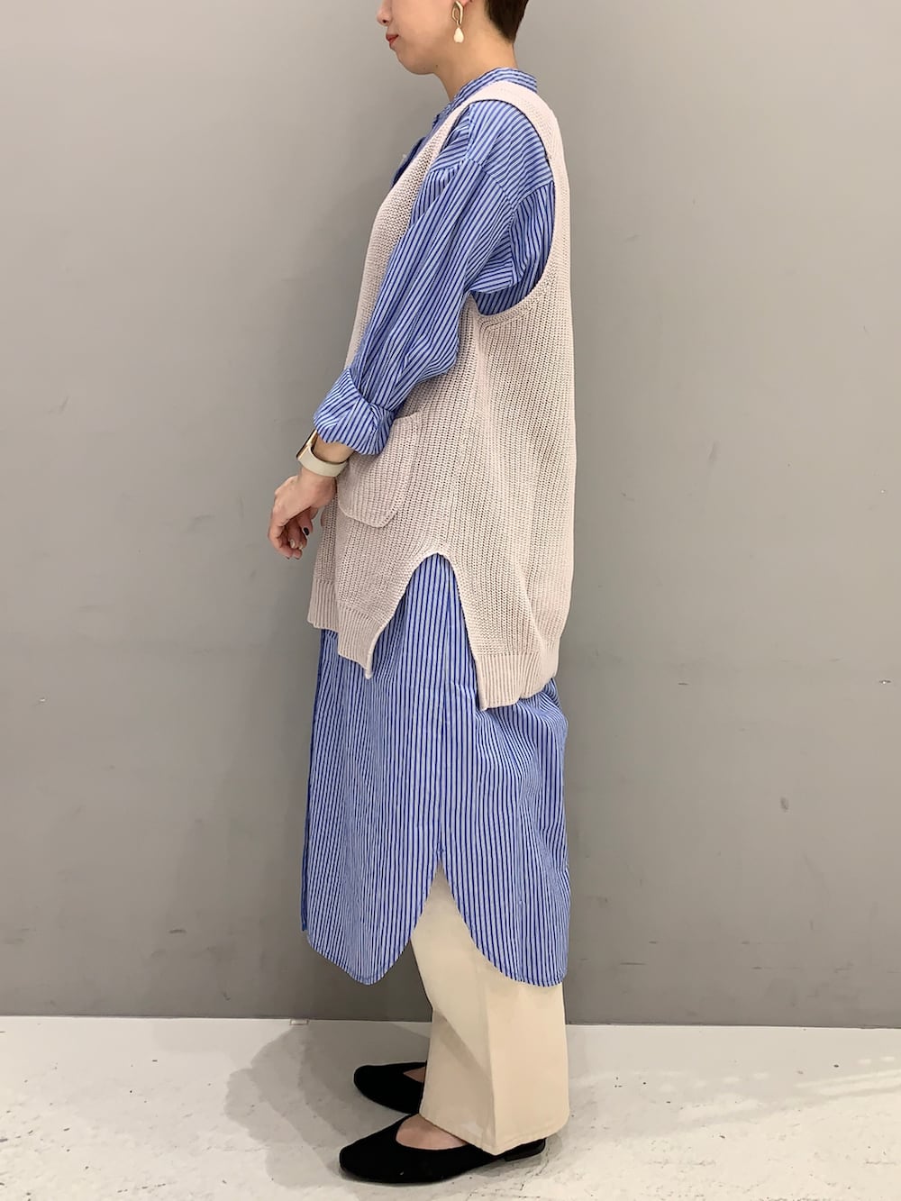 ブルー系のシャツワンピース、ベージュ系のベスト、ベージュ系のデニムパンツを着用したレディースの春コーディネートの2枚目の写真