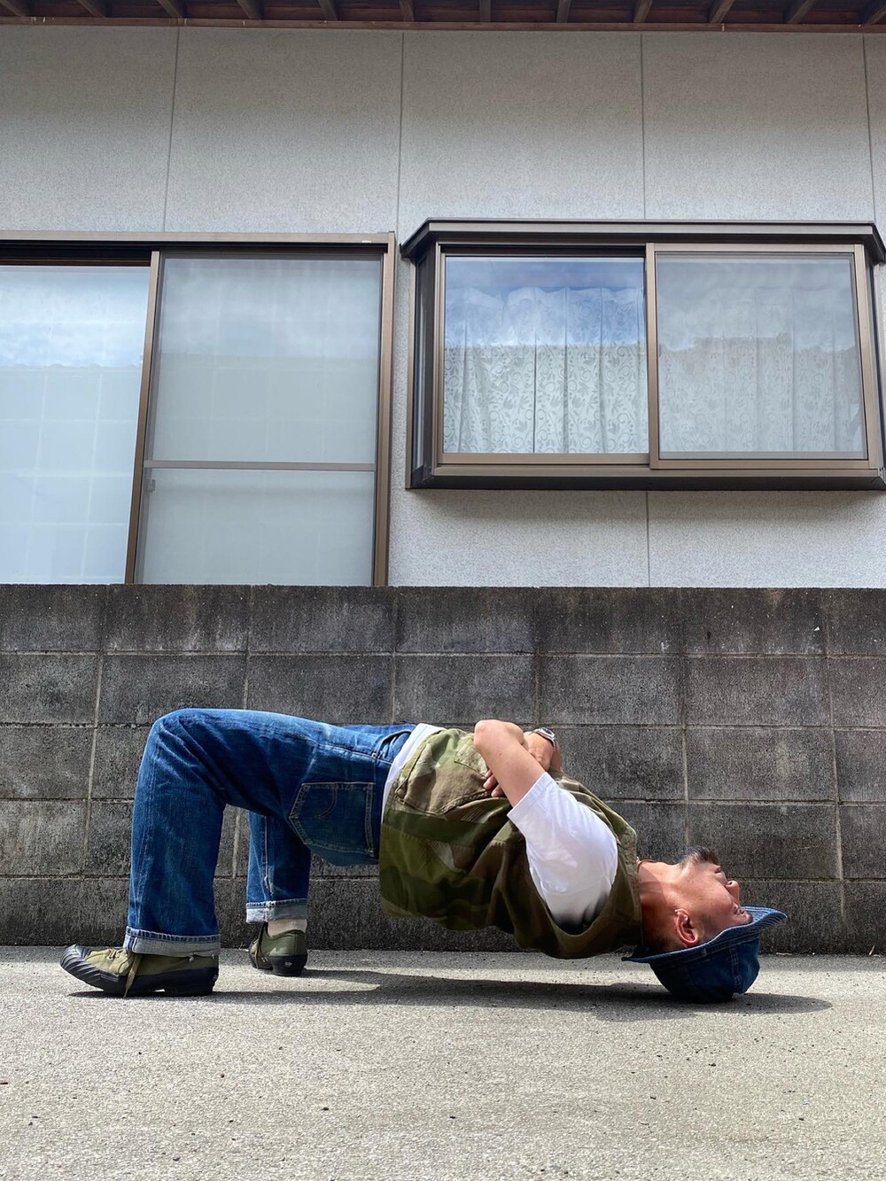 グリーン系のベスト、ブルー系のデニムパンツ、グリーン系のスニーカーを着用したメンズの夏コーディネートの4枚目の写真