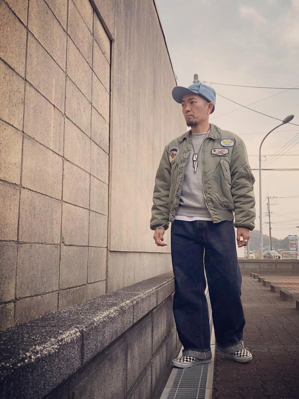 グリーン系のミリタリージャケット、グレー系のスウェット、ブルー系のデニムパンツを着用したメンズの冬コーディネートの2枚目の写真