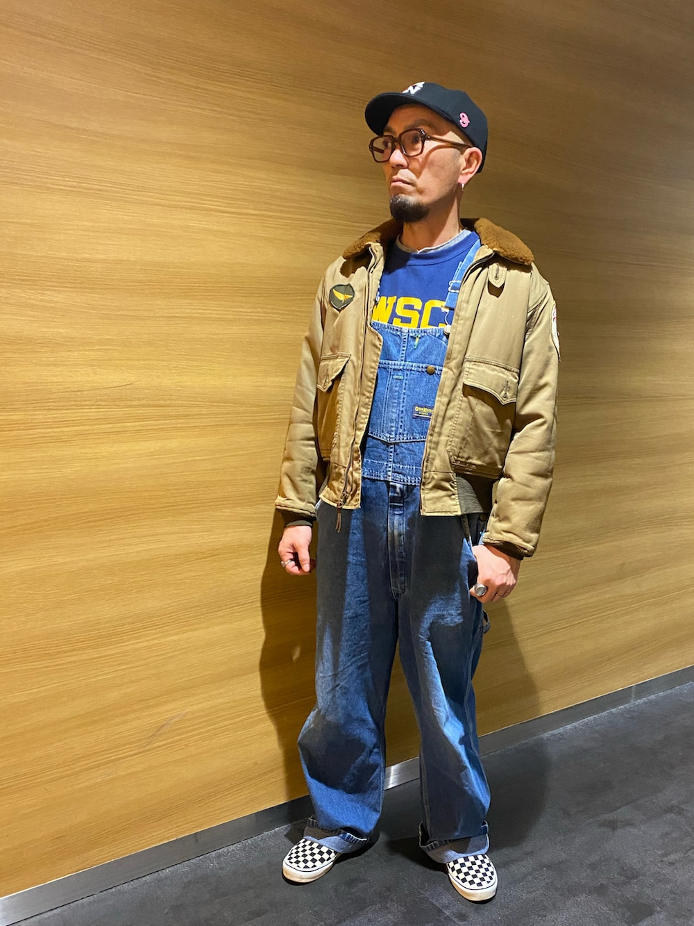 グリーン系のミリタリージャケット、ブルー系のサロペット/オーバーオール、ブルー系のスウェットを着用したメンズの冬コーディネートの2枚目の写真