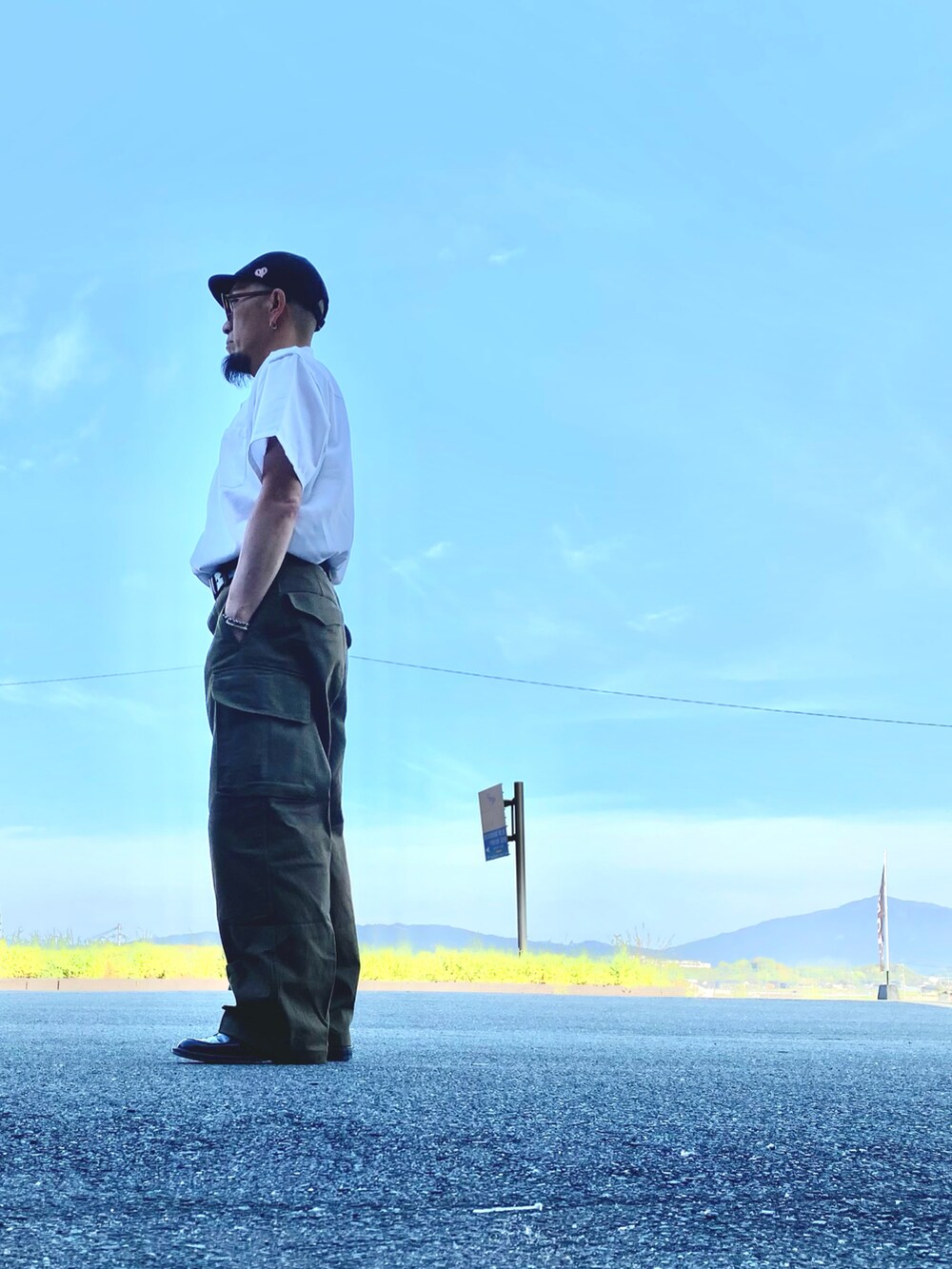 ホワイト系のシャツ/ブラウス、グリーン系のカーゴパンツ、ブラック系のシューズを着用したメンズの春コーディネートの2枚目の写真