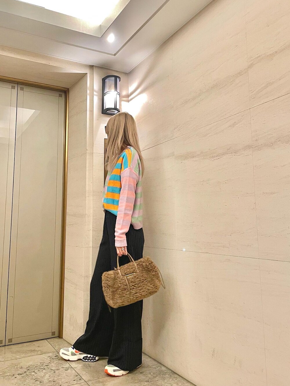 ブルー系のパンツ、その他のスニーカー、ブラウン系のハンドバッグを着用したレディースの秋コーディネートの3枚目の写真