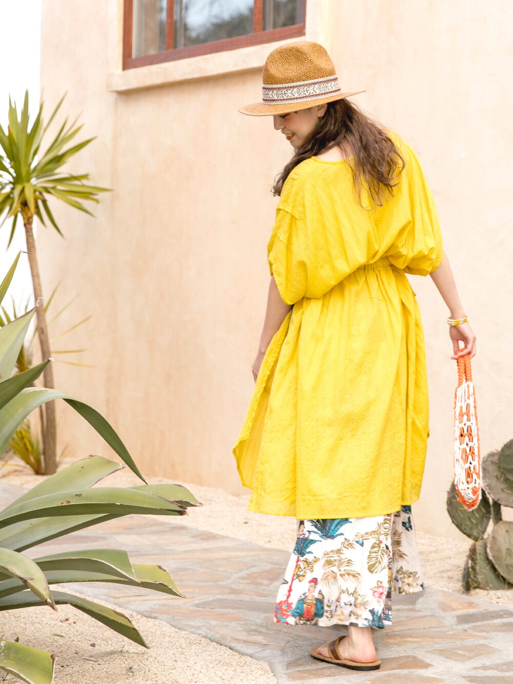 イエロー系のワンピース、オレンジ系のトートバッグ、ホワイト系のスカートを着用したレディースの夏コーディネートの4枚目の写真