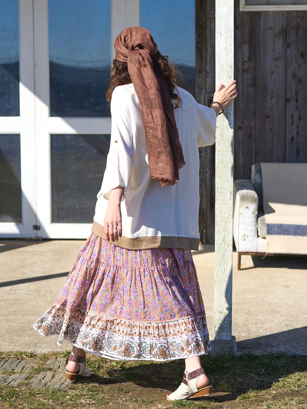 ベージュ系のスカート、ホワイト系のサンダル、ブラウン系のストール/ショールを着用したレディースの夏コーディネートの2枚目の写真