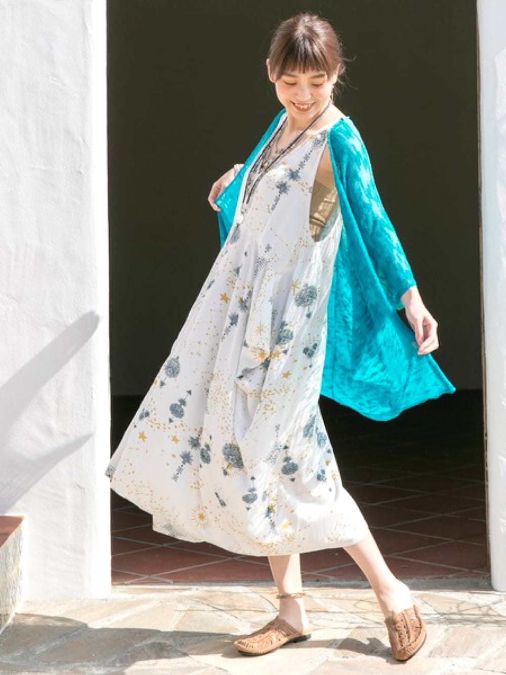 ホワイト系のワンピース、イエロー系のサンダル、ゴールド系のイヤーカフを着用したレディースの夏コーディネートの2枚目の写真