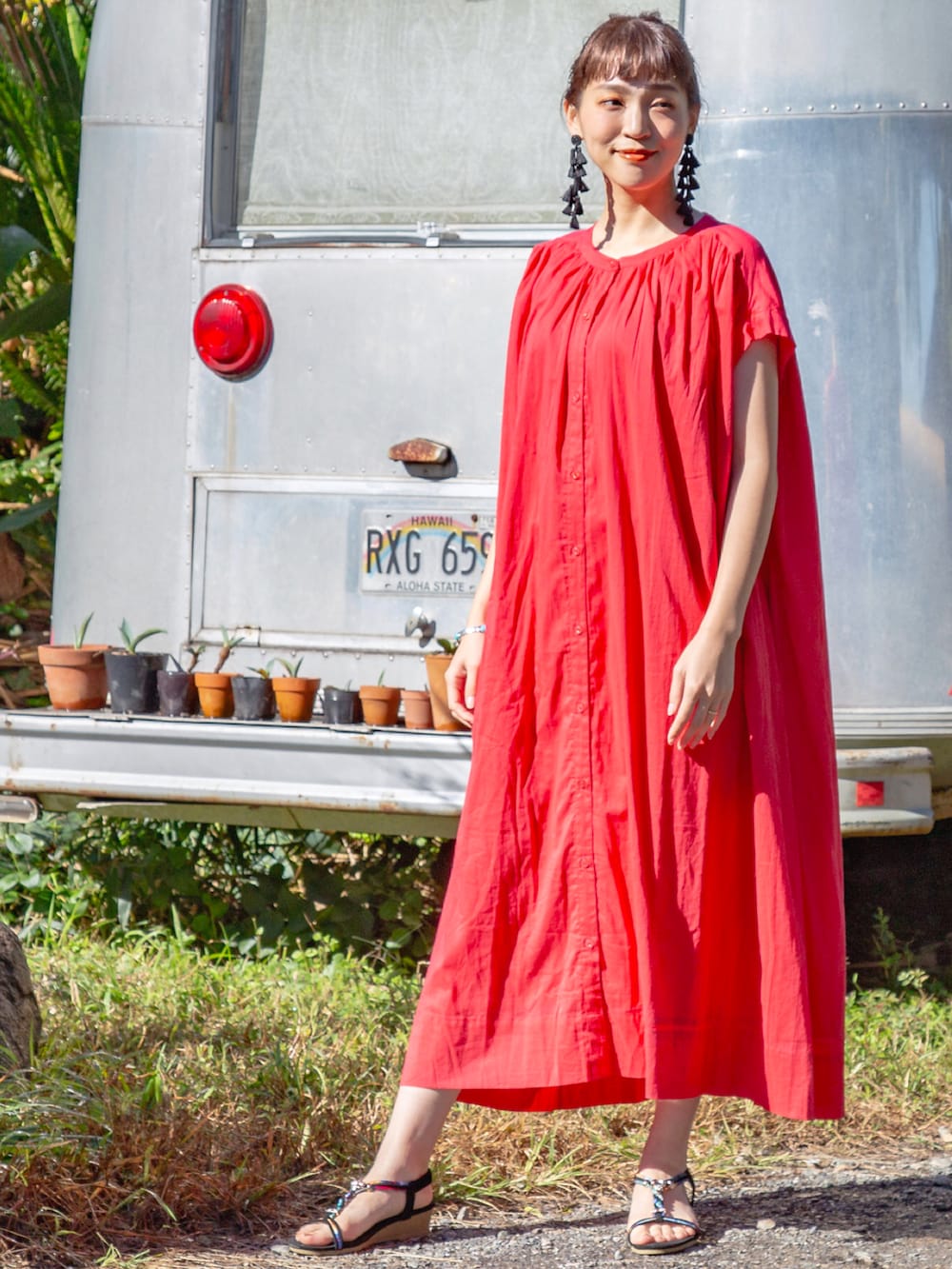 レッド系のワンピース、ブラック系のサンダル、ブラック系のピアス（両耳用）を着用したレディースの春コーディネートの2枚目の写真