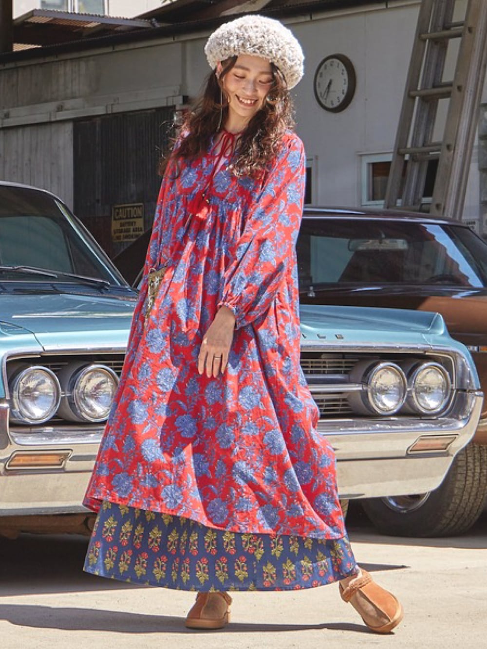 レッド系のワンピース、ブルー系のスカート、ゴールド系のショルダーバッグを着用したレディースの秋コーディネートの2枚目の写真