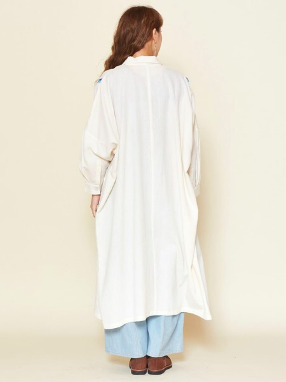 ベージュ系のシャツワンピース、ブルー系のデニムパンツ、ブラウン系のブーツを着用したレディースの春コーディネートの3枚目の写真