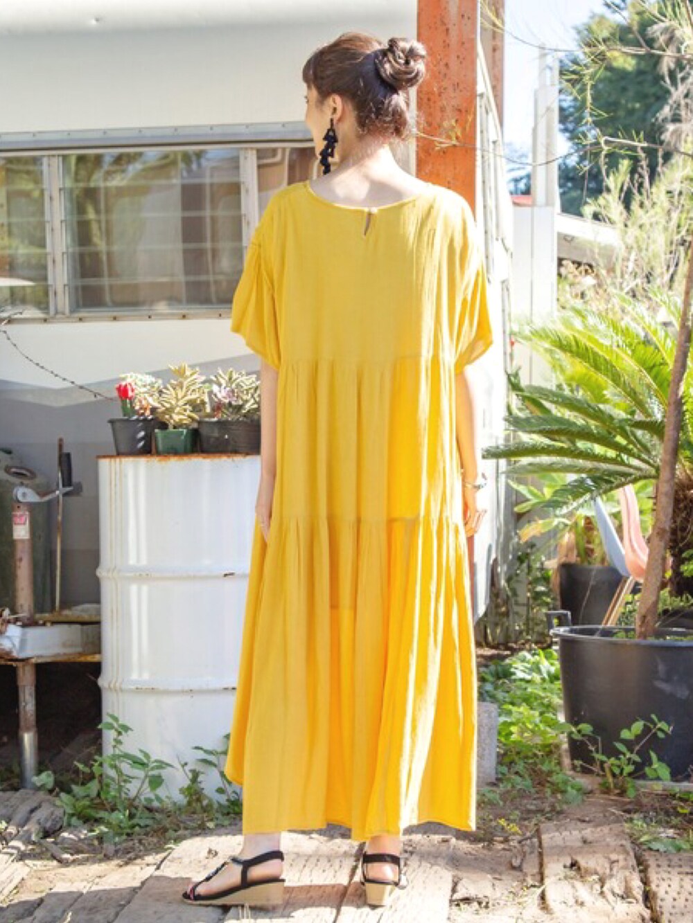 イエロー系のワンピース、ブラック系のサンダル、ブラック系のピアス（両耳用）を着用したレディースの春コーディネートの3枚目の写真