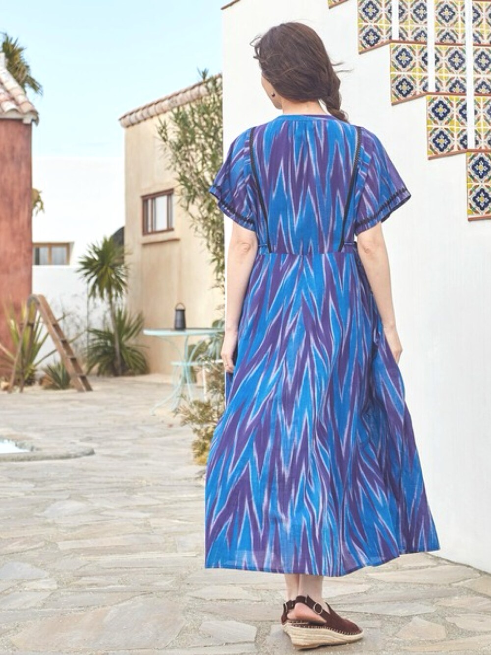 ブルー系のワンピース、ブラウン系のサンダル、ブルー系のピアス（両耳用）を着用したレディースの夏コーディネートの2枚目の写真