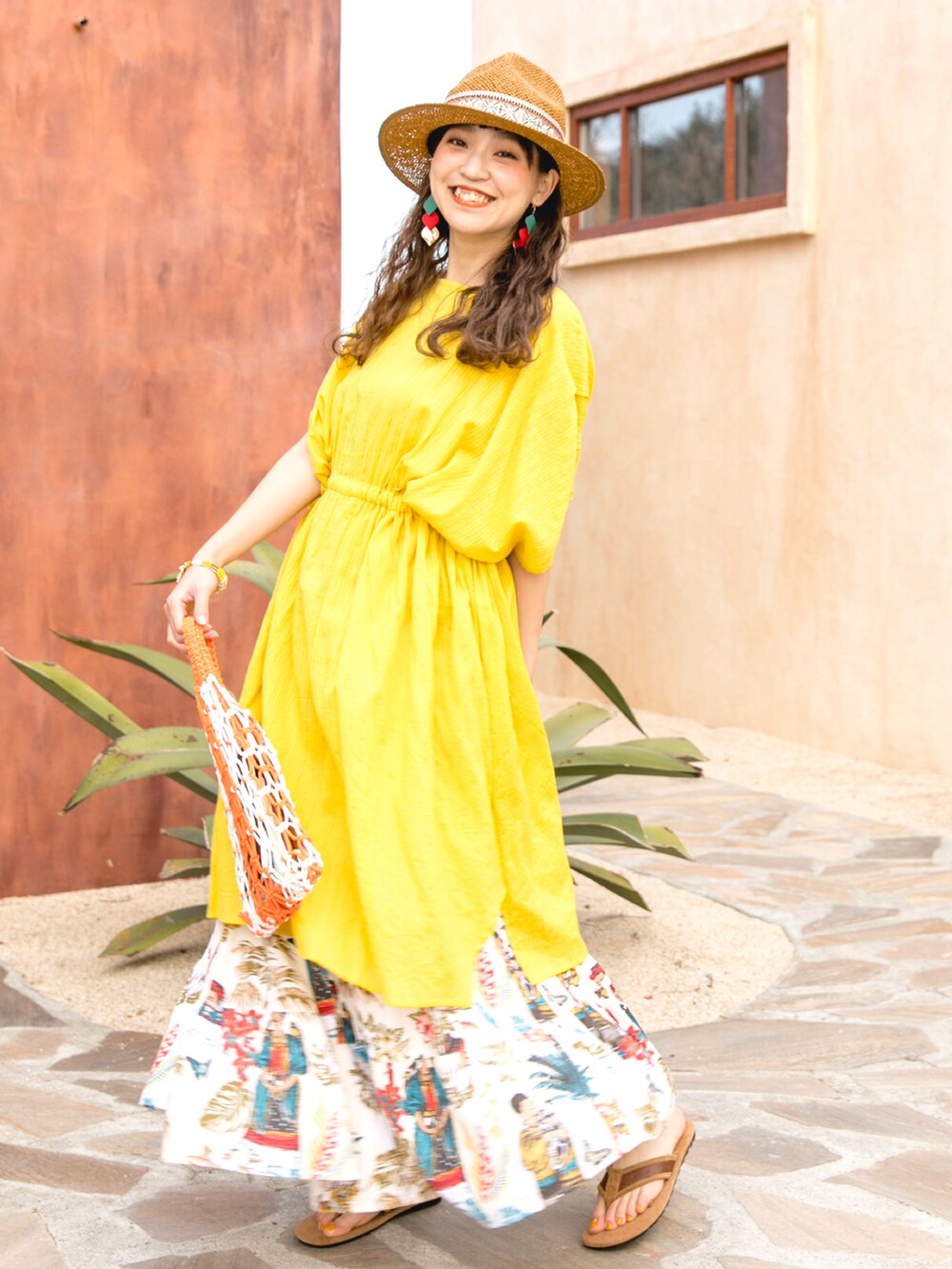 イエロー系のワンピース、オレンジ系のトートバッグ、ホワイト系のスカートを着用したレディースの夏コーディネートの5枚目の写真