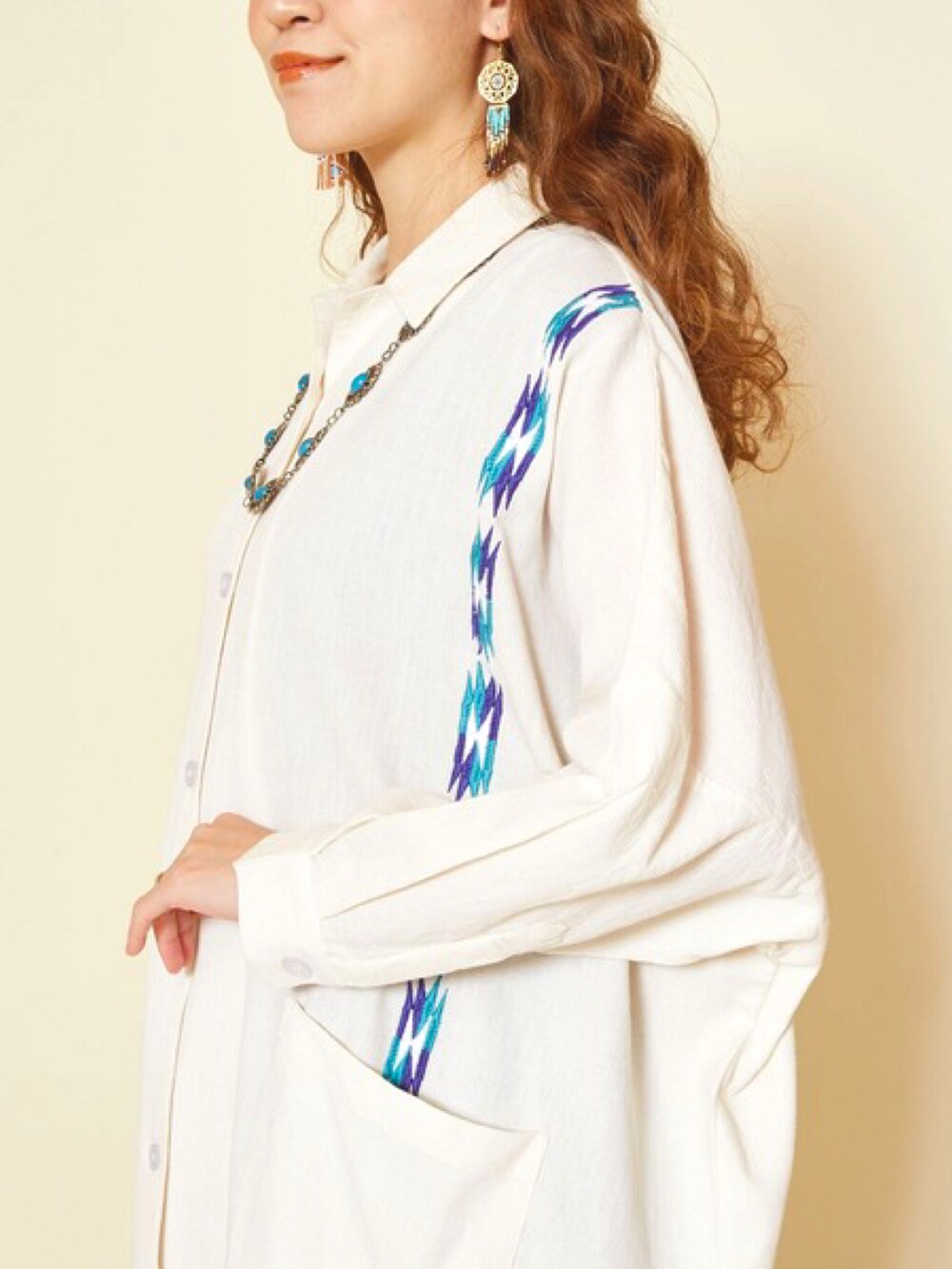 ベージュ系のシャツワンピース、ブルー系のデニムパンツ、ブラウン系のブーツを着用したレディースの春コーディネートの4枚目の写真