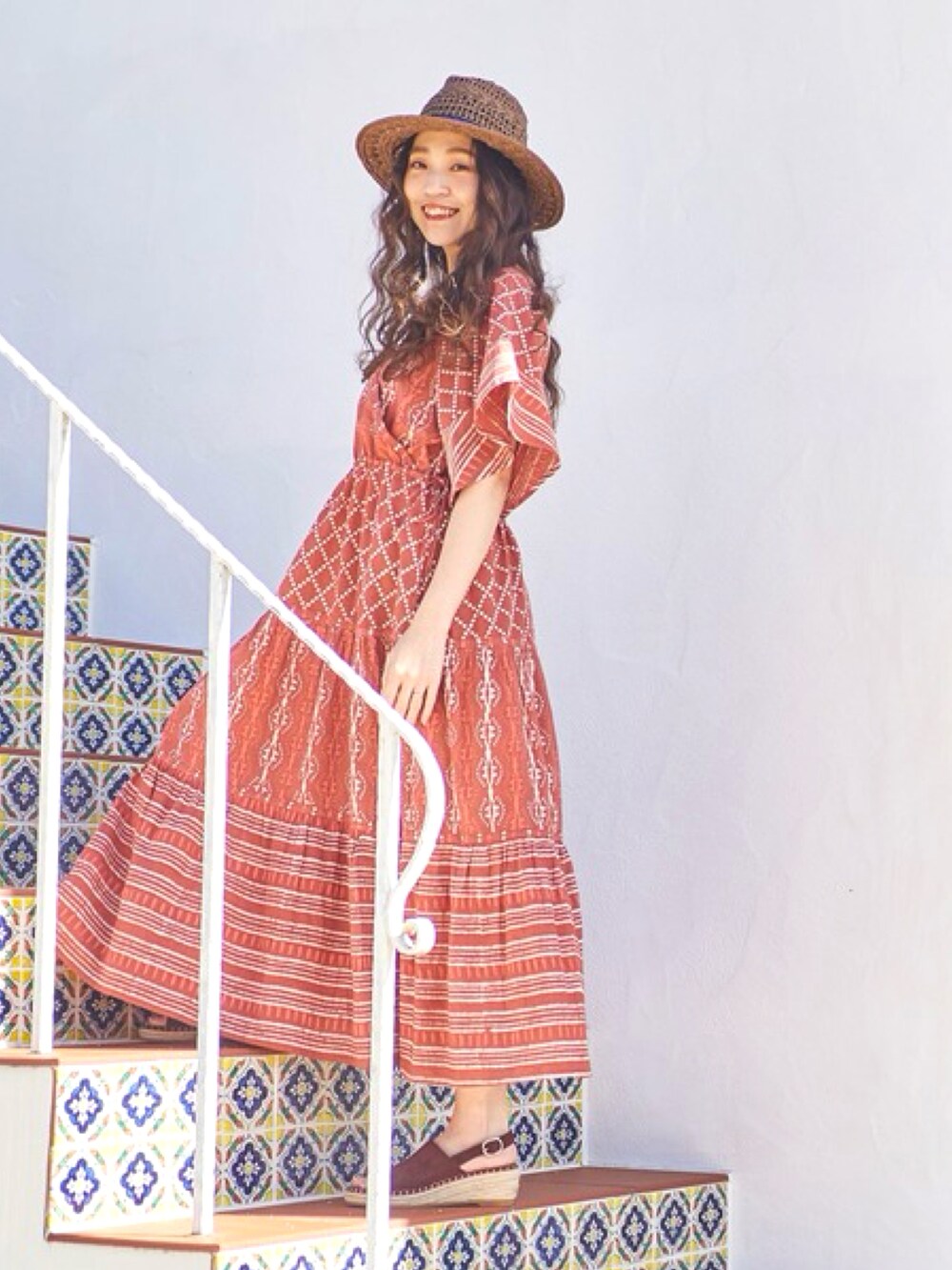 オレンジ系のワンピース、ブラウン系のサンダル、ブラウン系のハットを着用したレディースの夏コーディネートの3枚目の写真