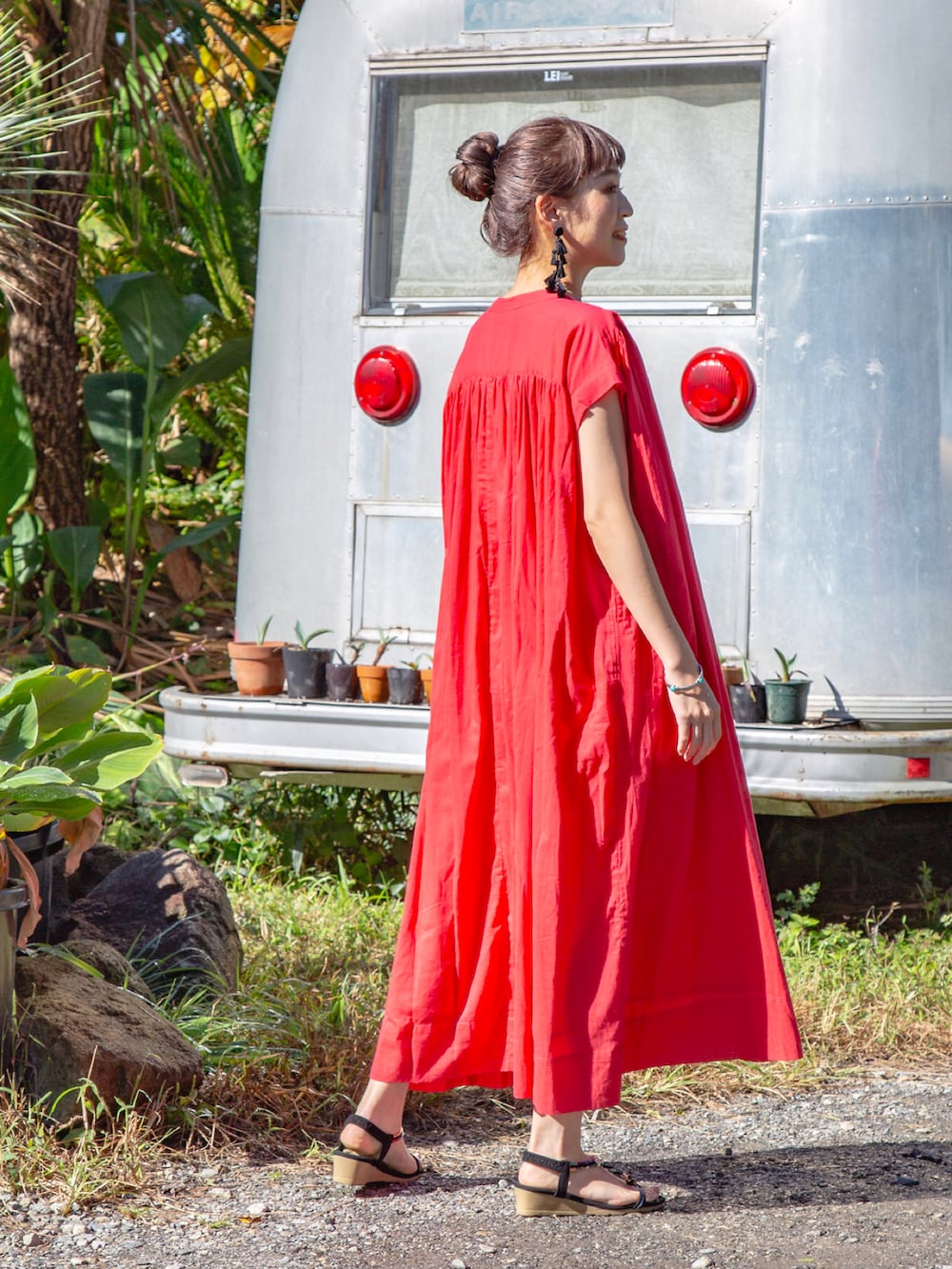 レッド系のワンピース、ブラック系のサンダル、ブラック系のピアス（両耳用）を着用したレディースの春コーディネートの3枚目の写真