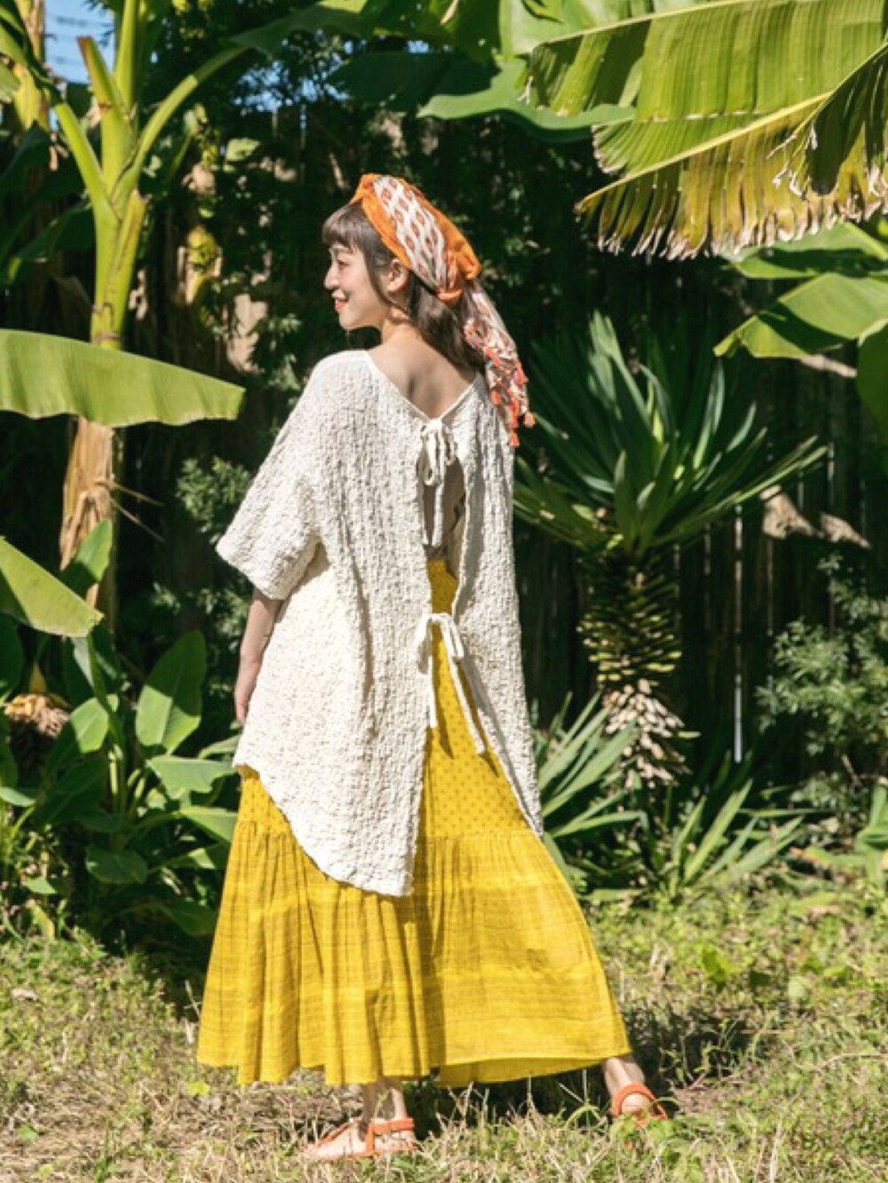 ホワイト系のTシャツ/カットソー、イエロー系のスカート、オレンジ系のサンダルを着用したレディースの冬コーディネートの3枚目の写真