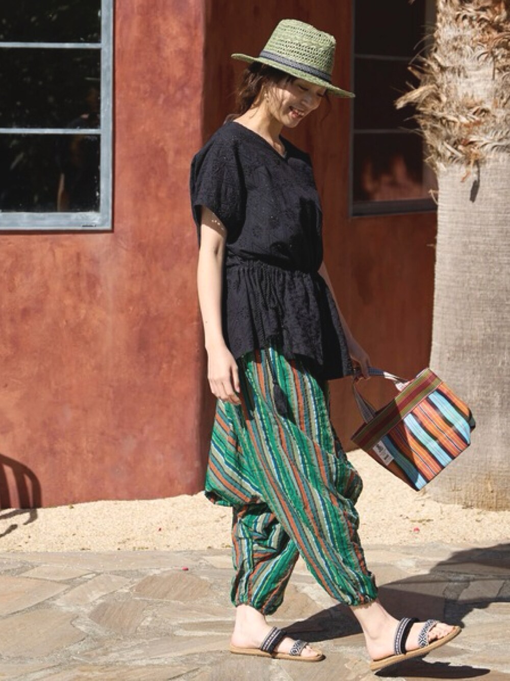 ブラック系のその他トップス、オレンジ系のトートバッグ、ブラック系のサンダルを着用したレディースの夏コーディネートの3枚目の写真