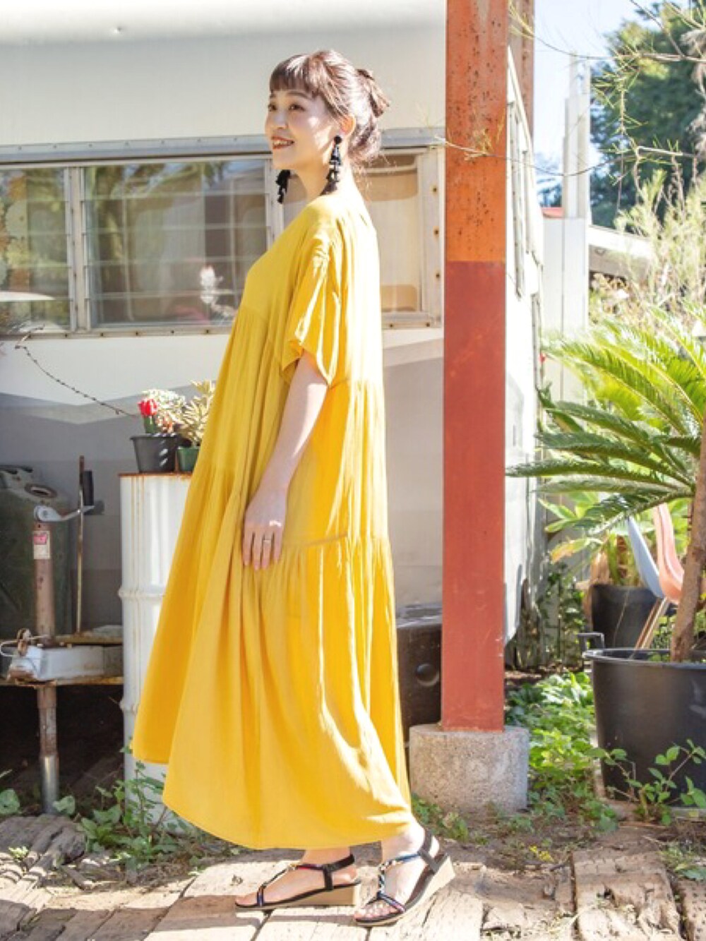 イエロー系のワンピース、ブラック系のサンダル、ブラック系のピアス（両耳用）を着用したレディースの春コーディネートの2枚目の写真