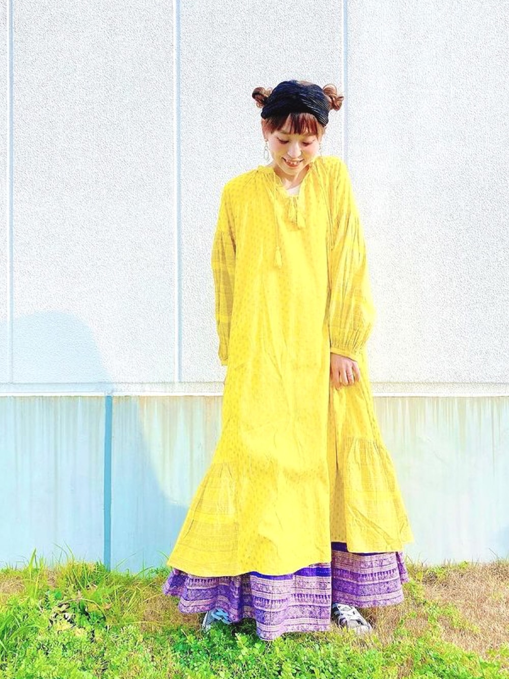 イエロー系のワンピース、パープル系のスカート、グレー系のスニーカーを着用したレディースの春コーディネートの2枚目の写真