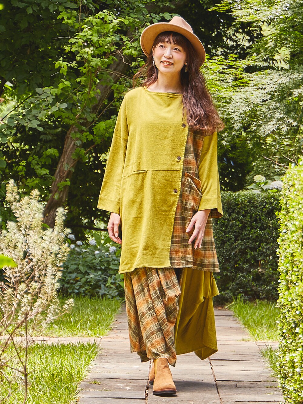 イエロー系のカーディガン/ボレロ、イエロー系のスカート、ベージュ系のブーツを着用したレディースの秋コーディネートの2枚目の写真
