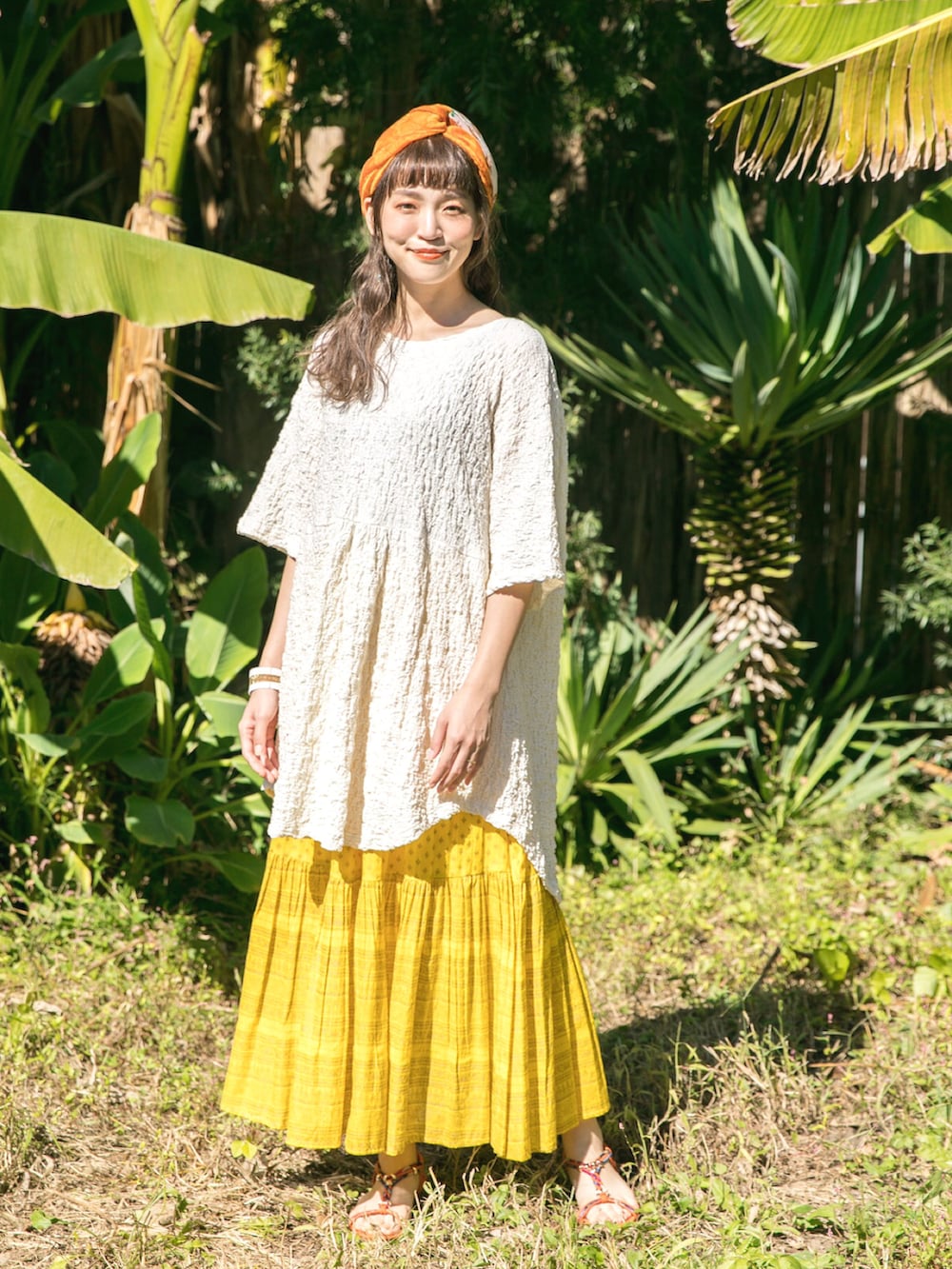 ホワイト系のTシャツ/カットソー、イエロー系のスカート、オレンジ系のサンダルを着用したレディースの冬コーディネートの2枚目の写真