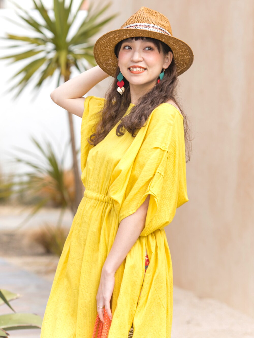 イエロー系のワンピース、オレンジ系のトートバッグ、ホワイト系のスカートを着用したレディースの夏コーディネートの3枚目の写真