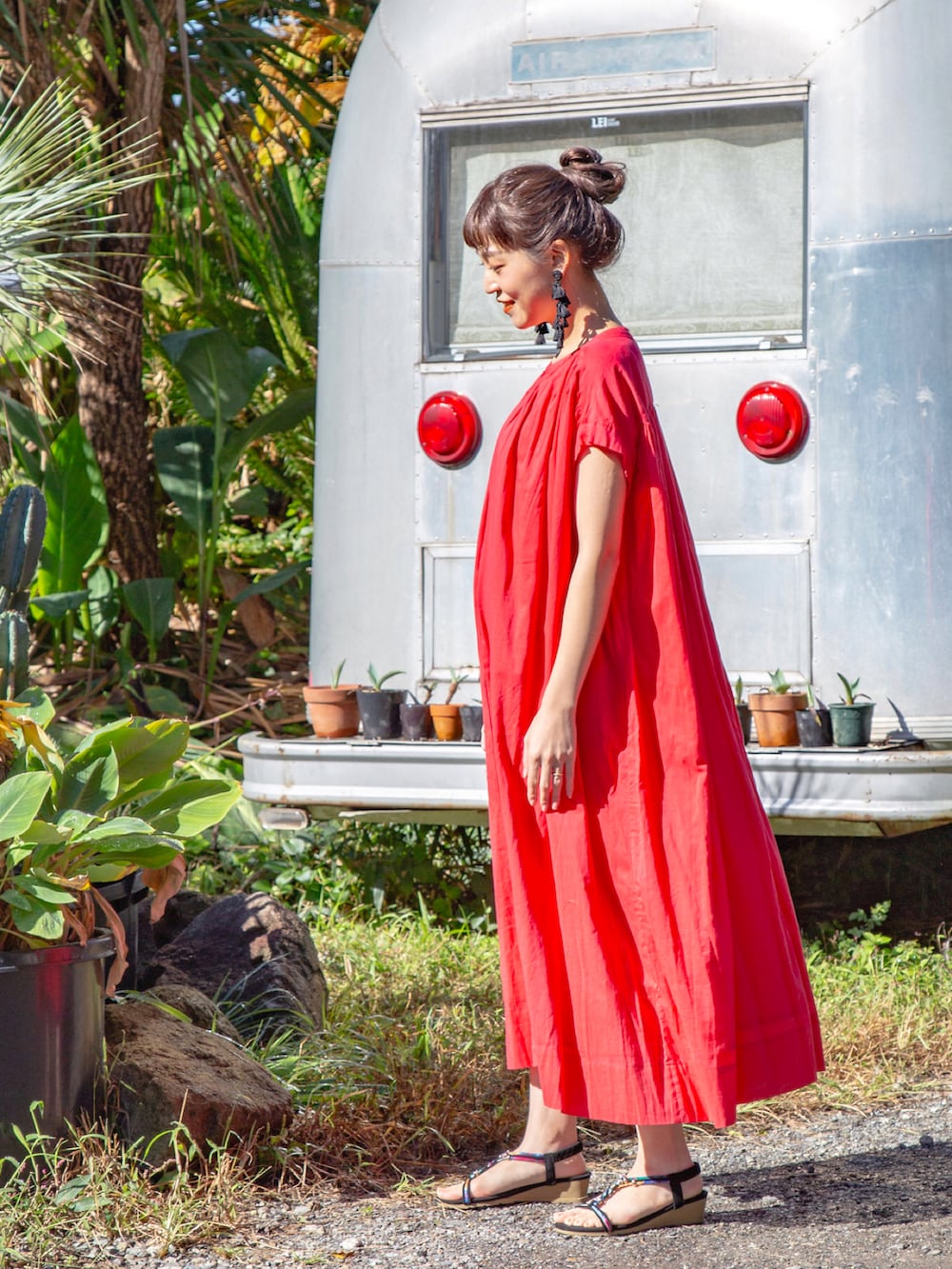 レッド系のワンピース、ブラック系のサンダル、ブラック系のピアス（両耳用）を着用したレディースの春コーディネートの4枚目の写真